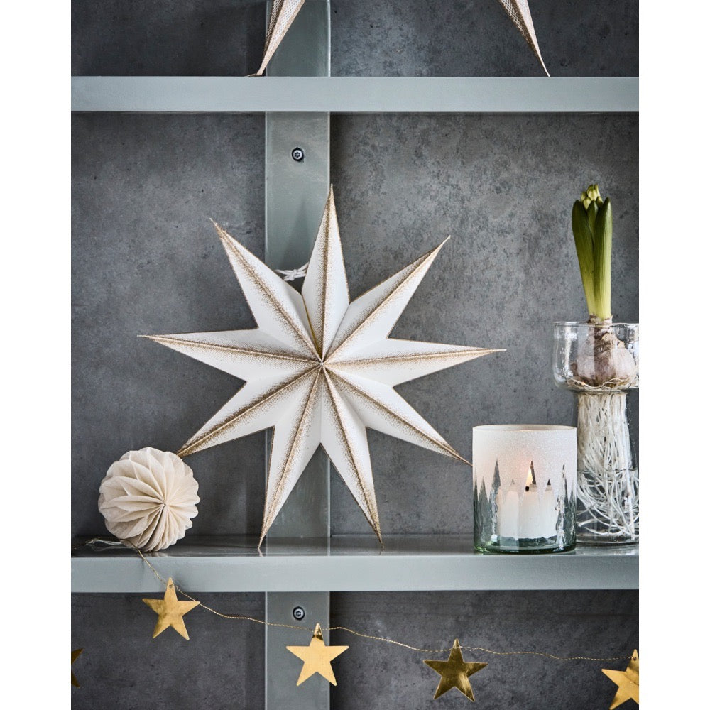Paper star on a shelf with Christmas decorations and a hyacinth