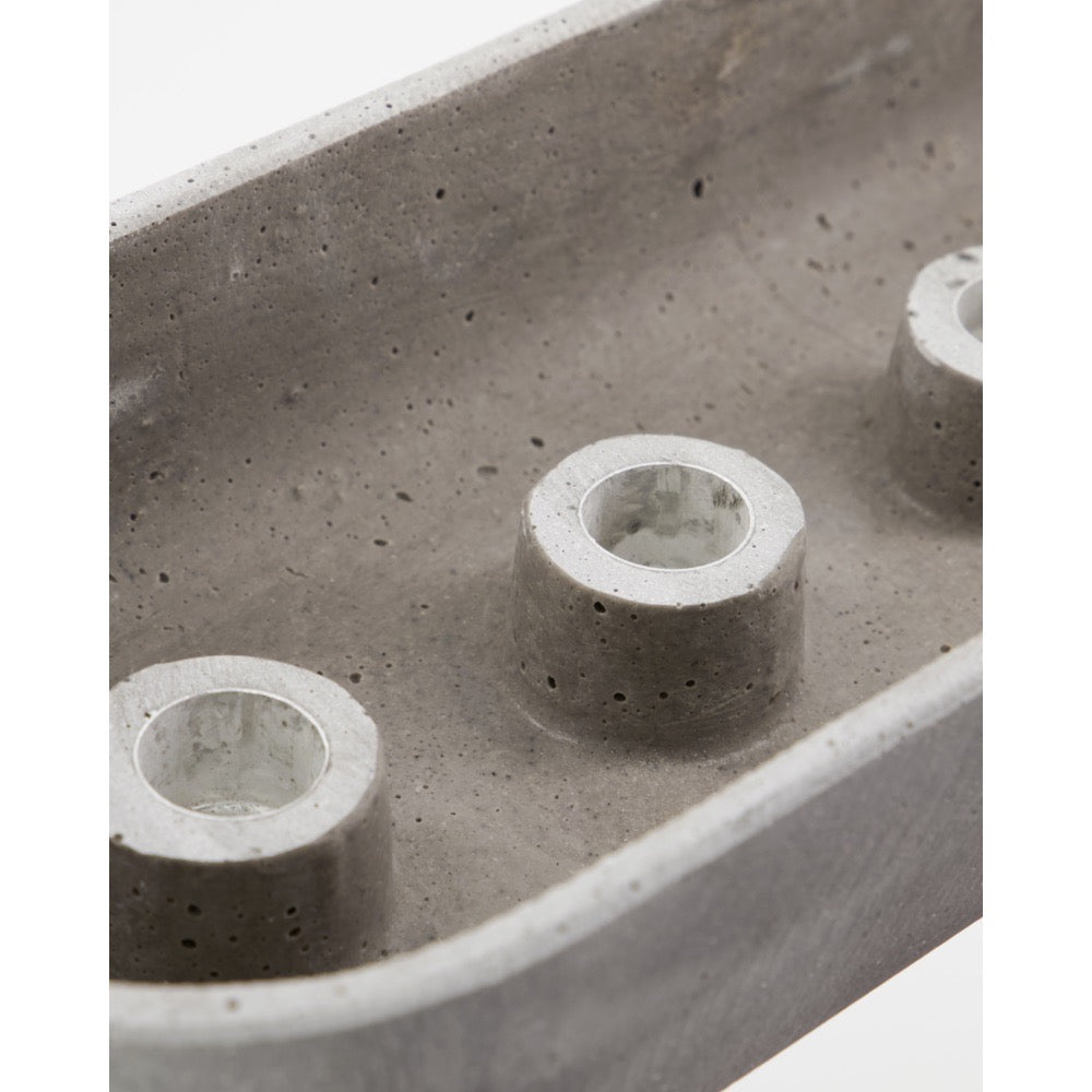 Close-up of candle holders at the base of a gray cement candlestick