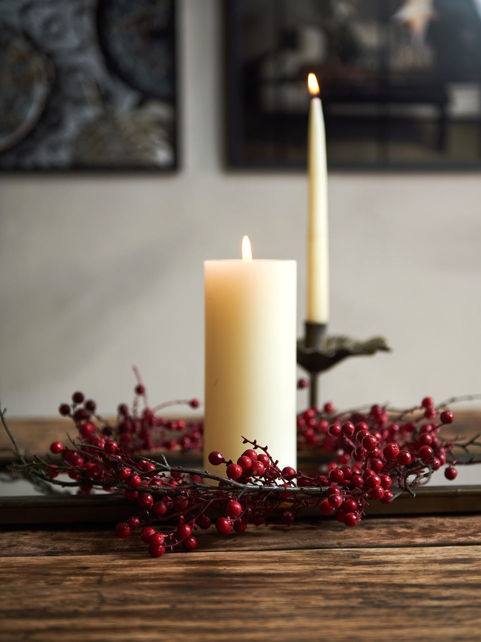 Wreath of red berries and branches surrounding a white pillar candle