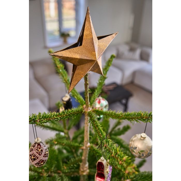 Guldfarvet topstjerne på juletræ.