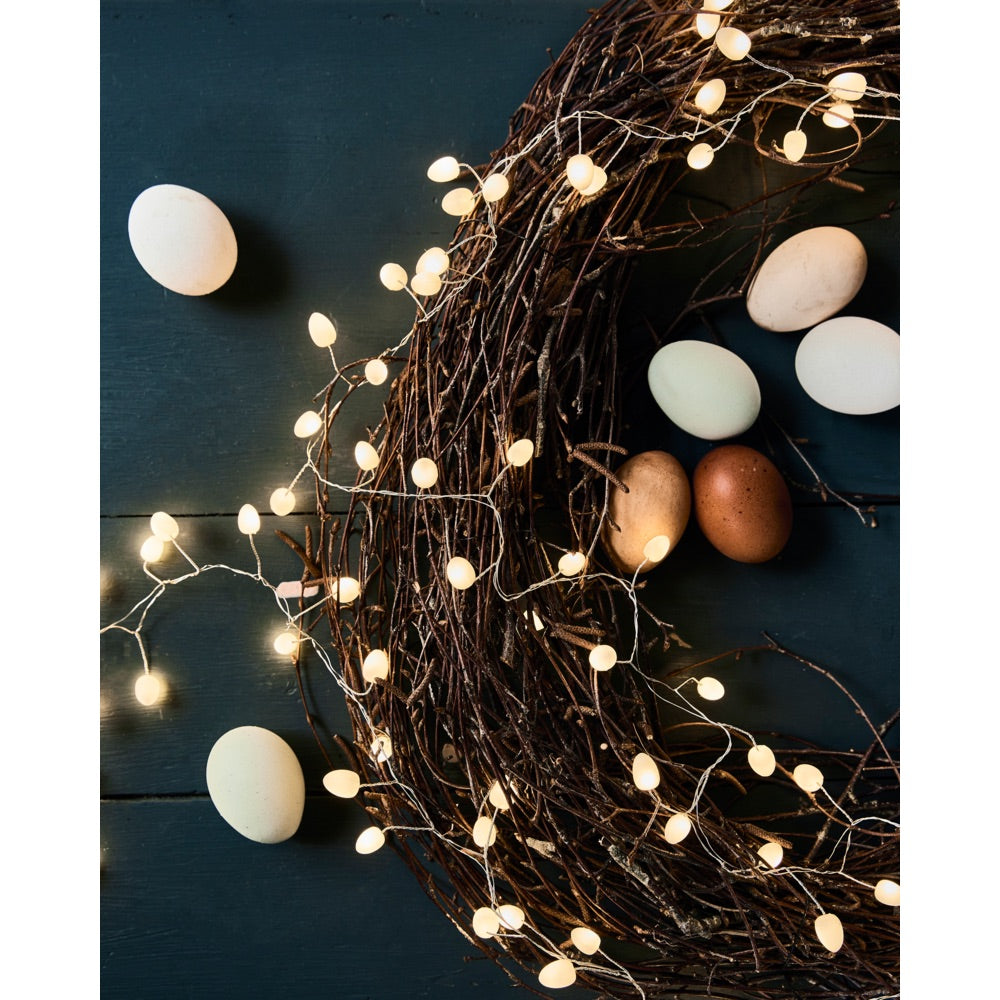 Wreath of branches with a string of lights from House Doctor wrapped around, decorated with eggs