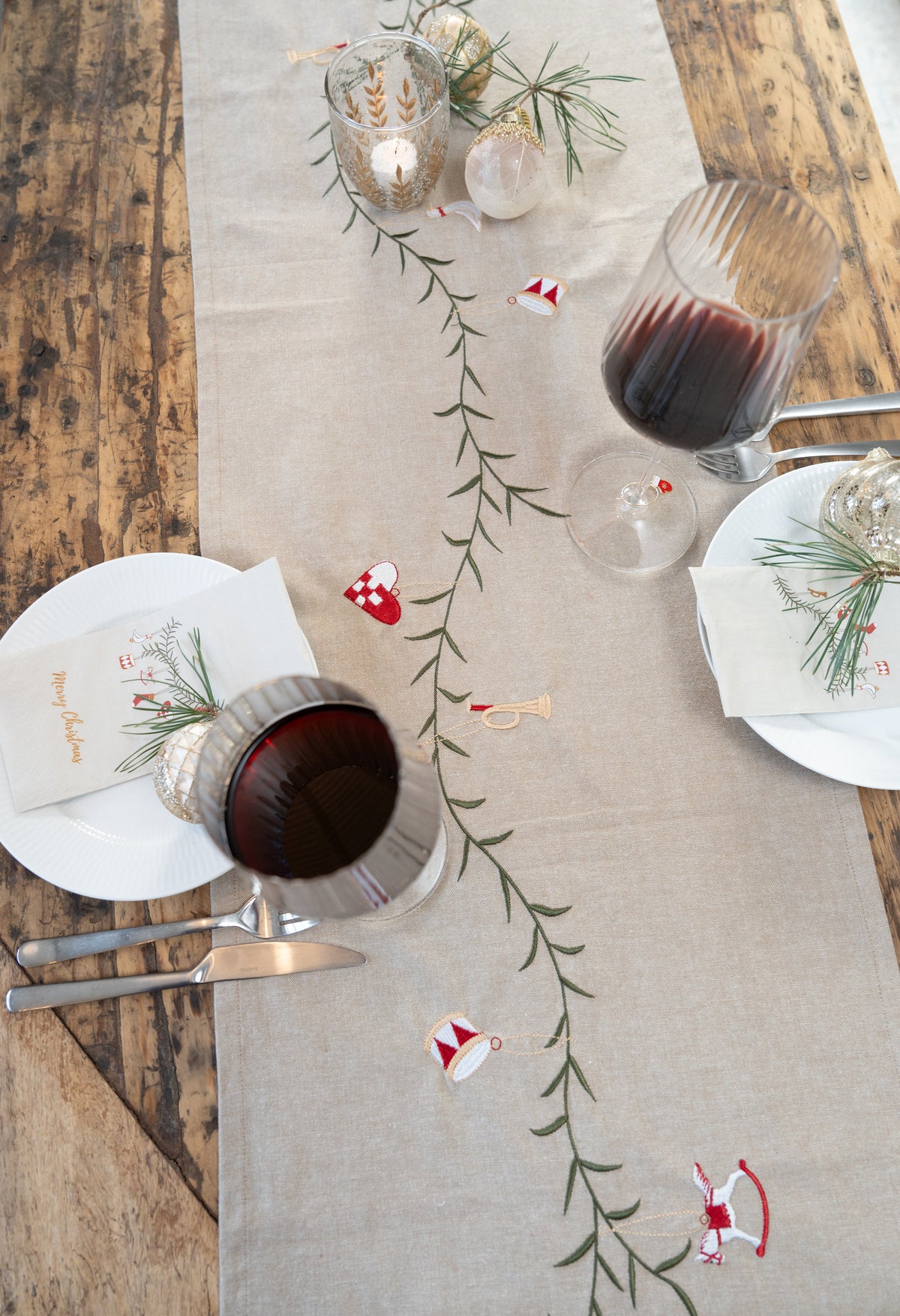 Table runner with a Christmas garland draping down the center of the dining table