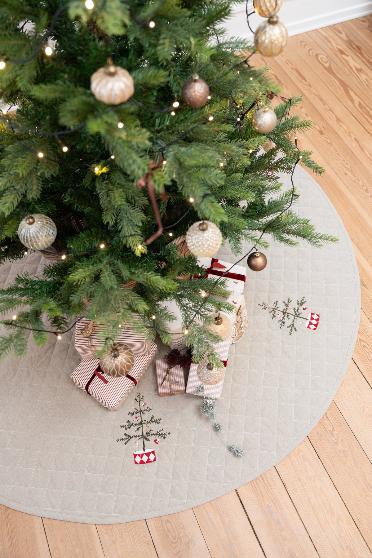 Decorated Christmas tree standing on a quilted tree skirt with embroidery from Speedtsberg