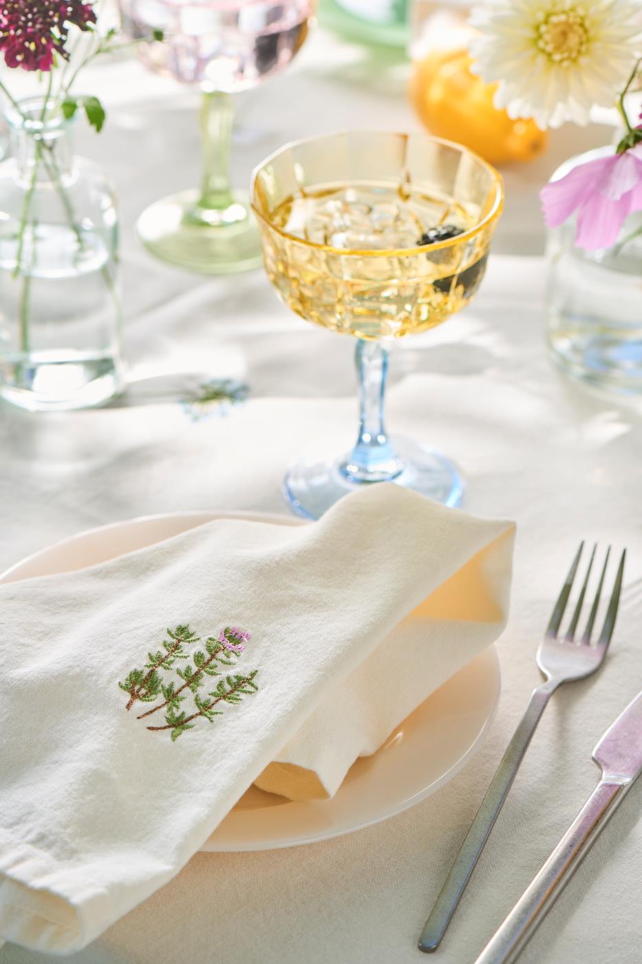 Dækket bord med dug og stofservietter med broderede blomster