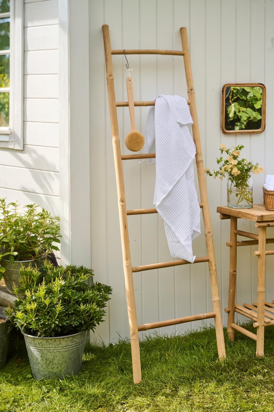 White bath towels hanging on a wooden ladder in the garden