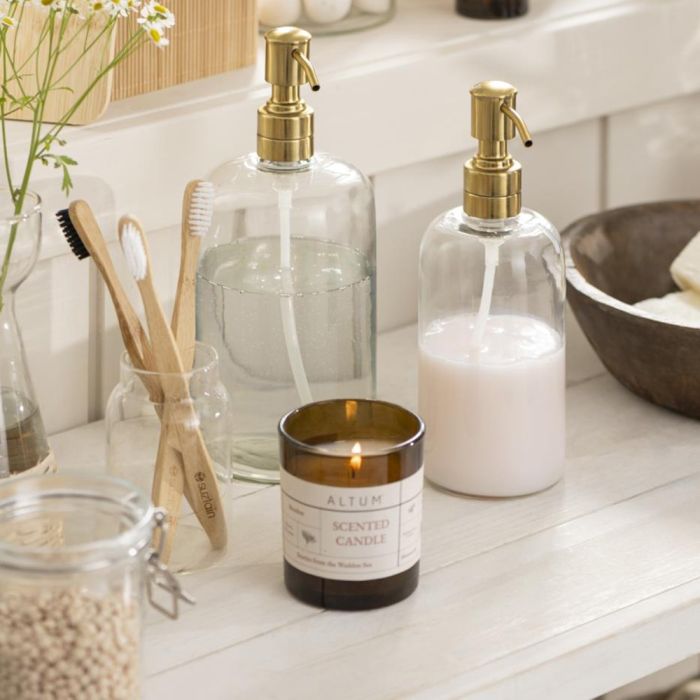 Ib Laursen sæbedispenser glas og messingfarvet pumpe med større dispenser med klar sæbe og et duftlys