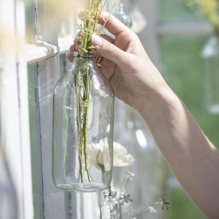 En hånd putter grønne planter i Ib Laursen dekorations glasflaske med metalwire 500 ml