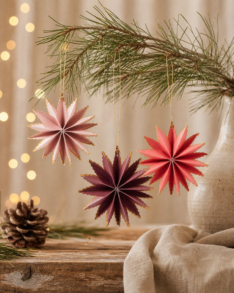 Purple, red and pink stars with gold-colored edges from Ib Laursen hanging on a branch