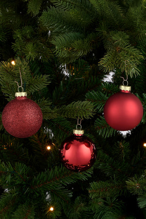 Matte, glossy and glittery glass Christmas bauble hanging on a Christmas tree