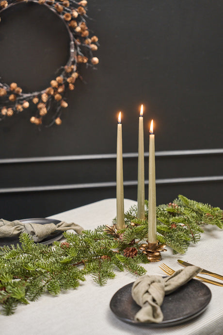 Fir garland draped along the center of a dining table with candles