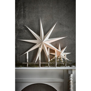 White stars from House Doctor decorating the fireplace with a chrome candle holder