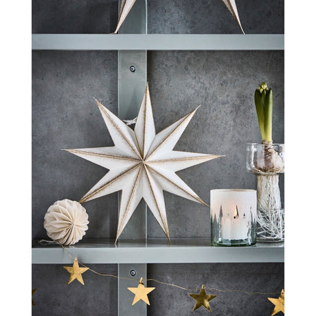Paper star on a shelf with Christmas decorations and a hyacinth