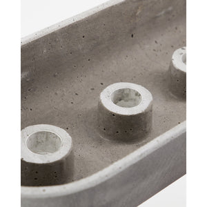 Close-up of candle holders at the base of a gray cement candlestick