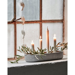 Candle holder with four taper candles decorated with olive branches on a windowsill