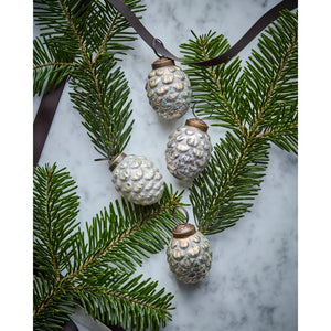 Small pine cones in a glass from House Doctor, decorated with spruce and a brown ribbon on a table