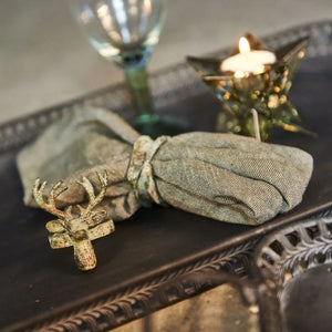 Servietring i antik grøn på stofserviet med servietring formet som hjort i forgrunden