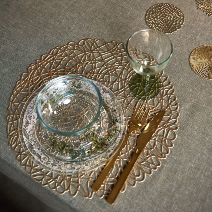 Guldfarvet dækkeserviet med hulmønster fra Speedtsberg under glasservice og guldbestik