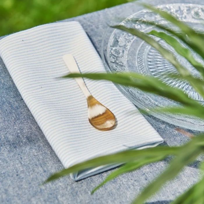 Speedtsberg stofserviet lyseblå striber foldet med guldske ovenpå
