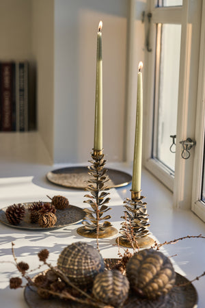 Patterned decorative tray in antique gold with candleholders, Christmas baubles and natural decorations in a cozy Christmas arrangement by the window