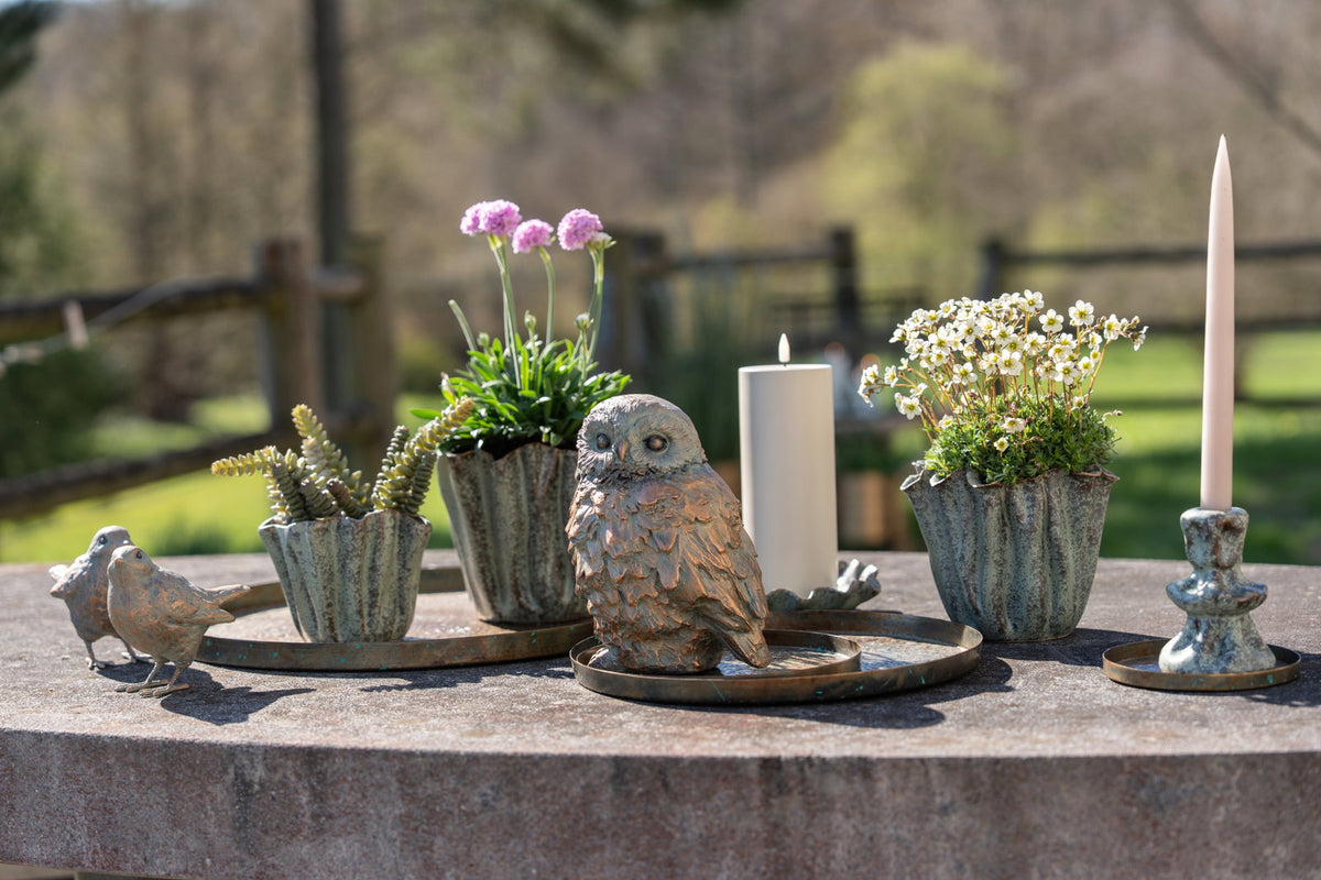 Rustic metal tray from Speedtsberg used as a decorative display with small flowers, candles, and natural accents on an outdoor table