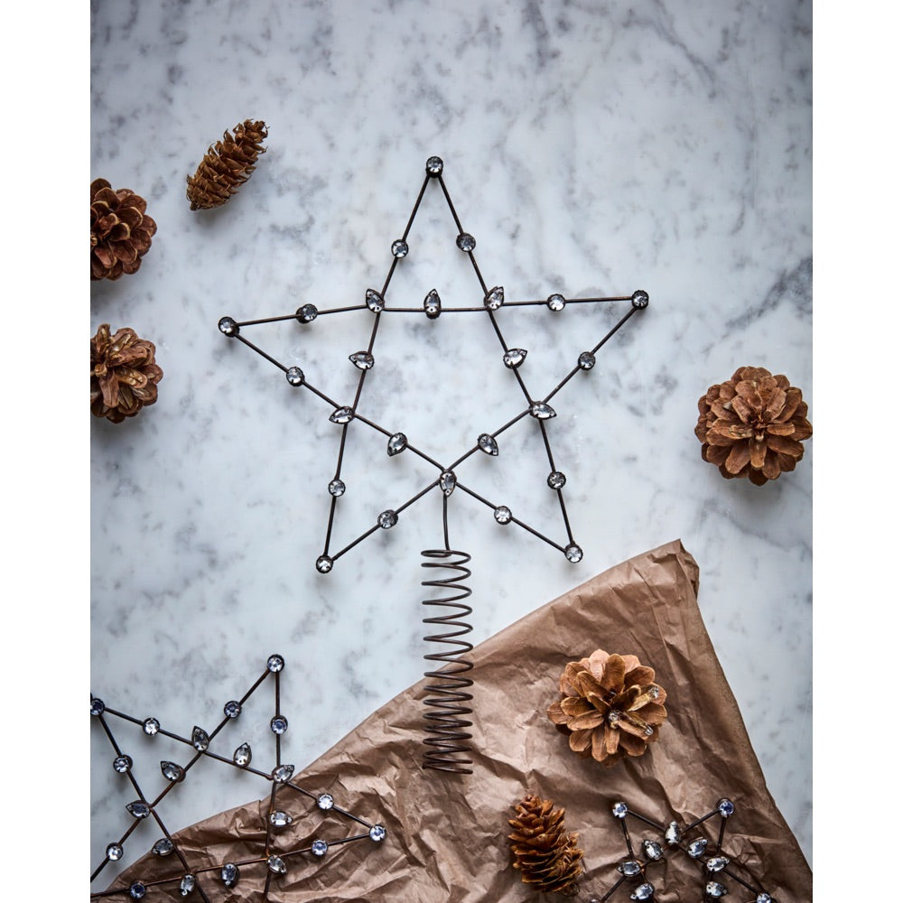 Beaded tree-top star on a table with pine cones