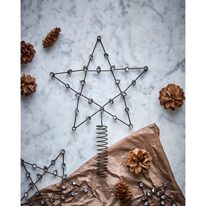 Beaded tree-top star on a table with pine cones