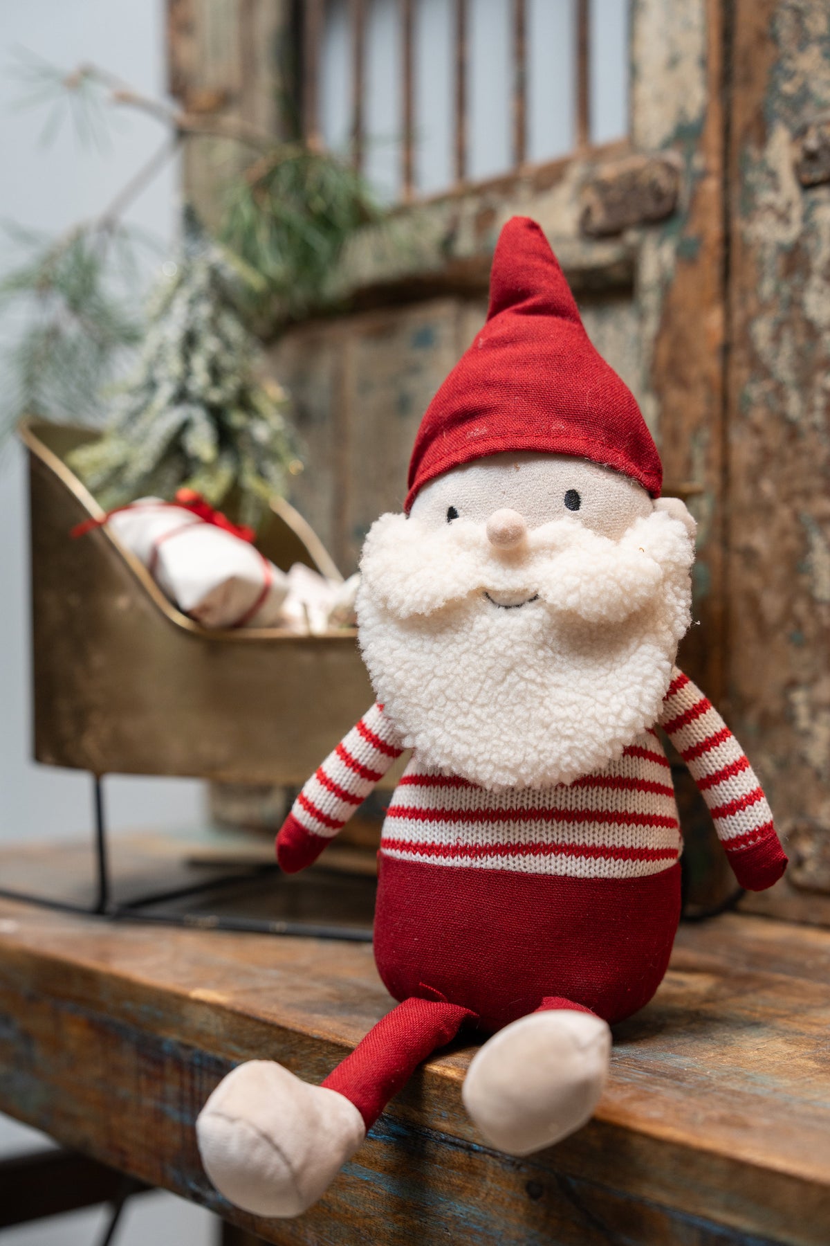 Santa Max fabric figure from Speedtsberg sitting on a table in front of a gold-colored sleigh