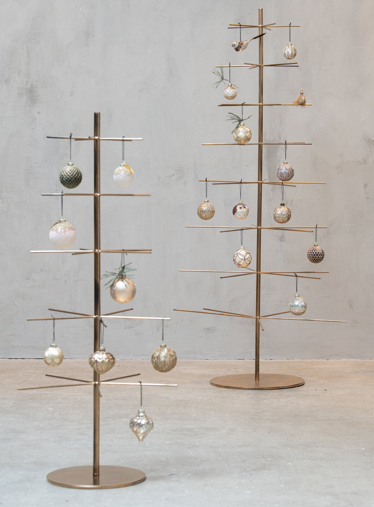 Two gold-colored metal Christmas trees decorated with ornaments from Speedtsberg