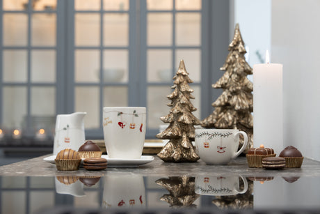 Christmas tableware with a garland on a table with gold-colored Christmas trees