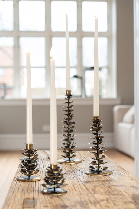 Pinecone candle holders from Speedtsberg with white candles, decorating a table