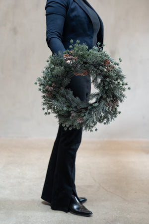 Wreath in mixed fir with frosted effect and cones, 45 cm — held in hand for scale