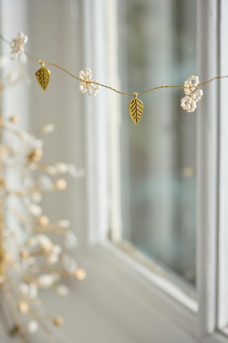 Garland with white beads and gold-tone leaves from Ib Laursen, hanging as a window decoration