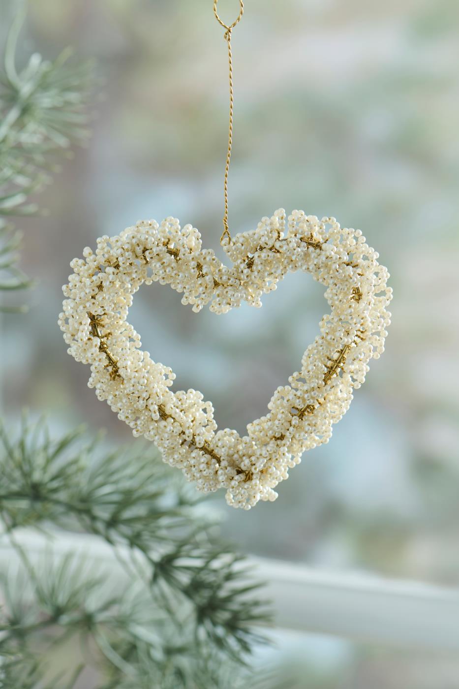 Heart with white beads from Ib Laursen hanging in front of a window