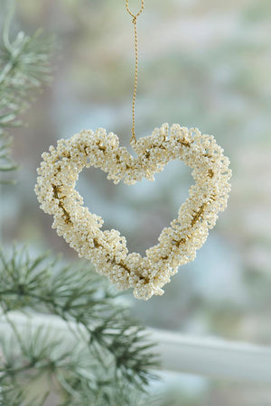 Heart with white beads from Ib Laursen hanging in front of a window