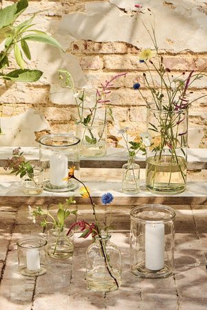 Cylinderglas og glasvaser med blomster i på trappe udenfor