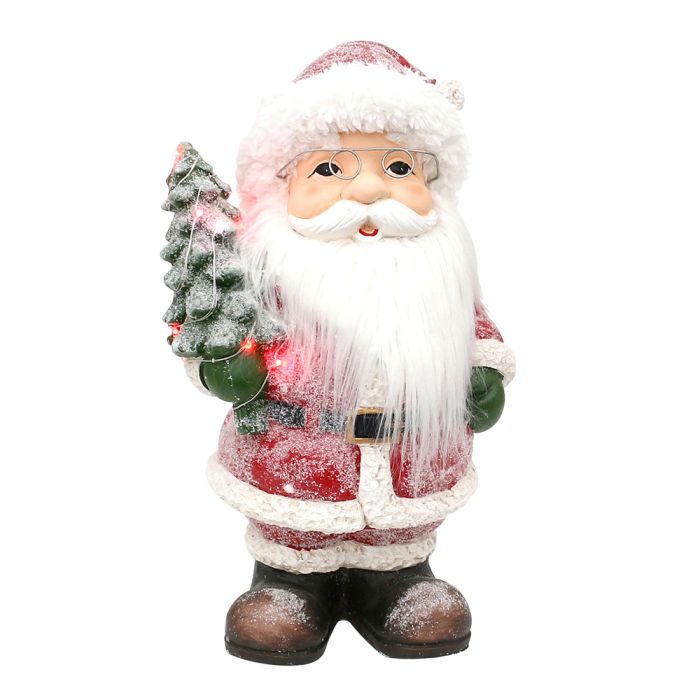 Stor Julemand med venlig ansigt, langt skæg og nissebriller i klassiske julefarver og grønne luffer. Julemanden holder et juletræ i hånden med lys i. 