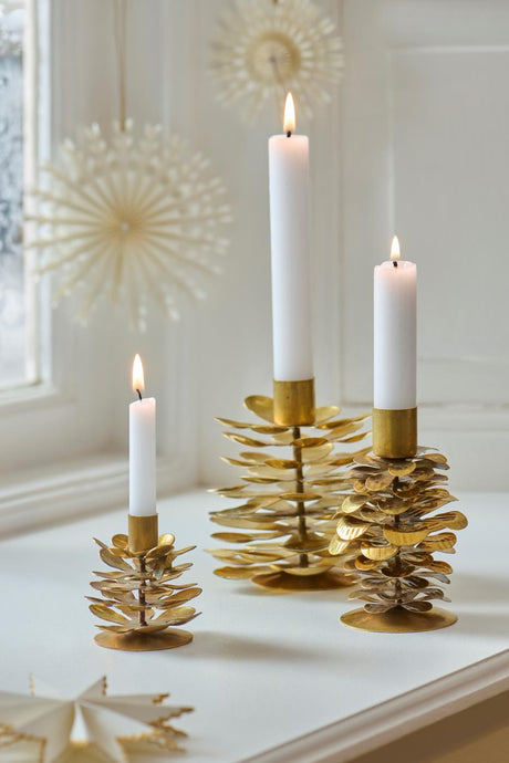 Brass pinecone candle holders by Ib Laursen, with paper-cut decorations in the background
