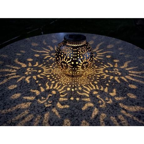 Solcellelampe med solmønster i mørke, der skaber stemningsfuldt lys