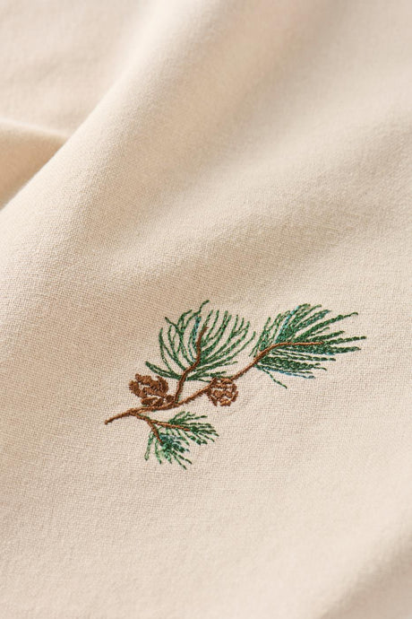 Close-up of motif on Tradition fabric napkin: pine branch with cones from Ib Laursen