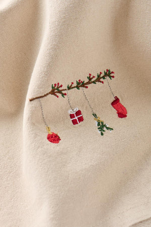 Close-up of a motif on a linen-colored cloth napkin featuring a traditional branch-hanging Christmas ornament from Ib Laursen