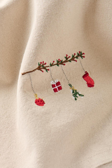 Close-up of a motif on a linen-colored cloth napkin featuring a traditional branch-hanging Christmas ornament from Ib Laursen