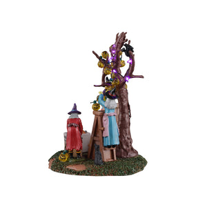 Decorating The Spooky Tree med hekse, der pynter op med lys til Halloween fra Lemax