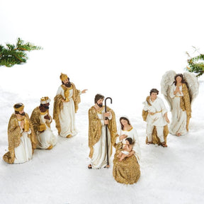 Krybbespilsfigurer i guld og hvide farver. Josef betragter Jomfru Maria og Jesusbarnet, sammen med de 3 visemænd, en hyrde og en engel. Figurerne er adskilte og dermed flytbare. Fra Pobra. 