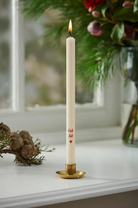 Candles with 'Merry Christmas' in a gold-colored holder on a windowsill