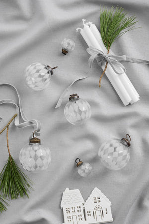 Mini clear glass Christmas baubles with engraved harlequin pattern on a table with other Christmas decorations from Ib Laursen