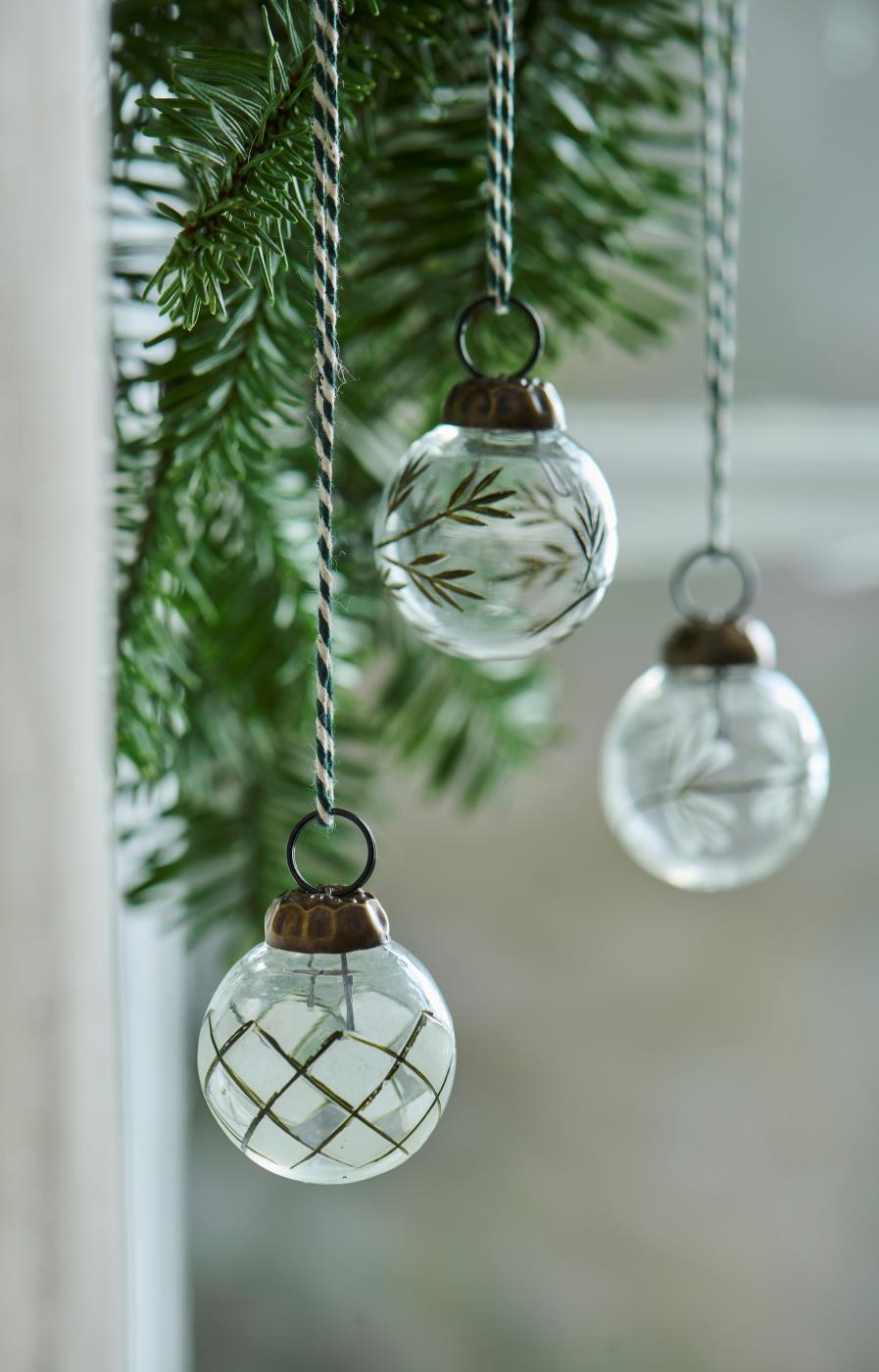 Mini Christmas baubles from Ib Laursen with an engraved green pattern, hanging on twine amid fir branches
