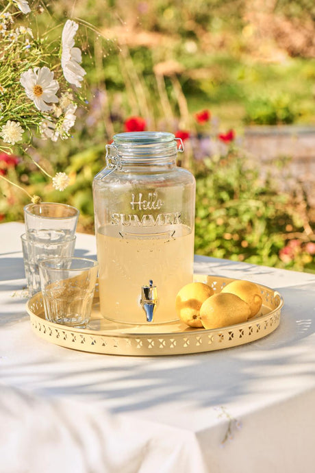Saftdispenser med tappehane i klart glas fyldet med saft