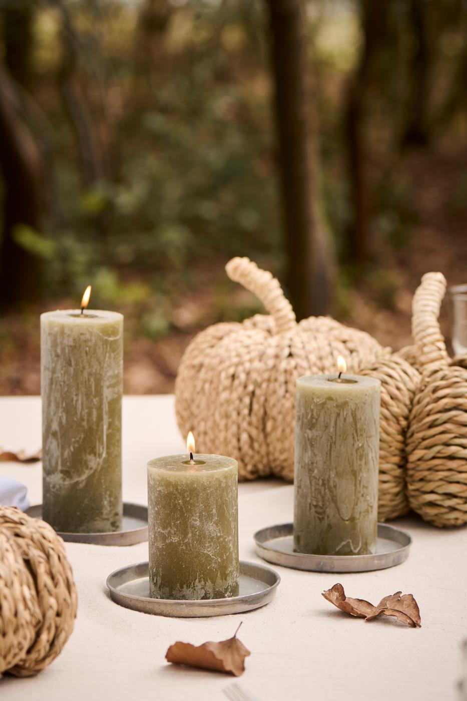 Olive-green pillar candles decorate an autumn table with pumpkins