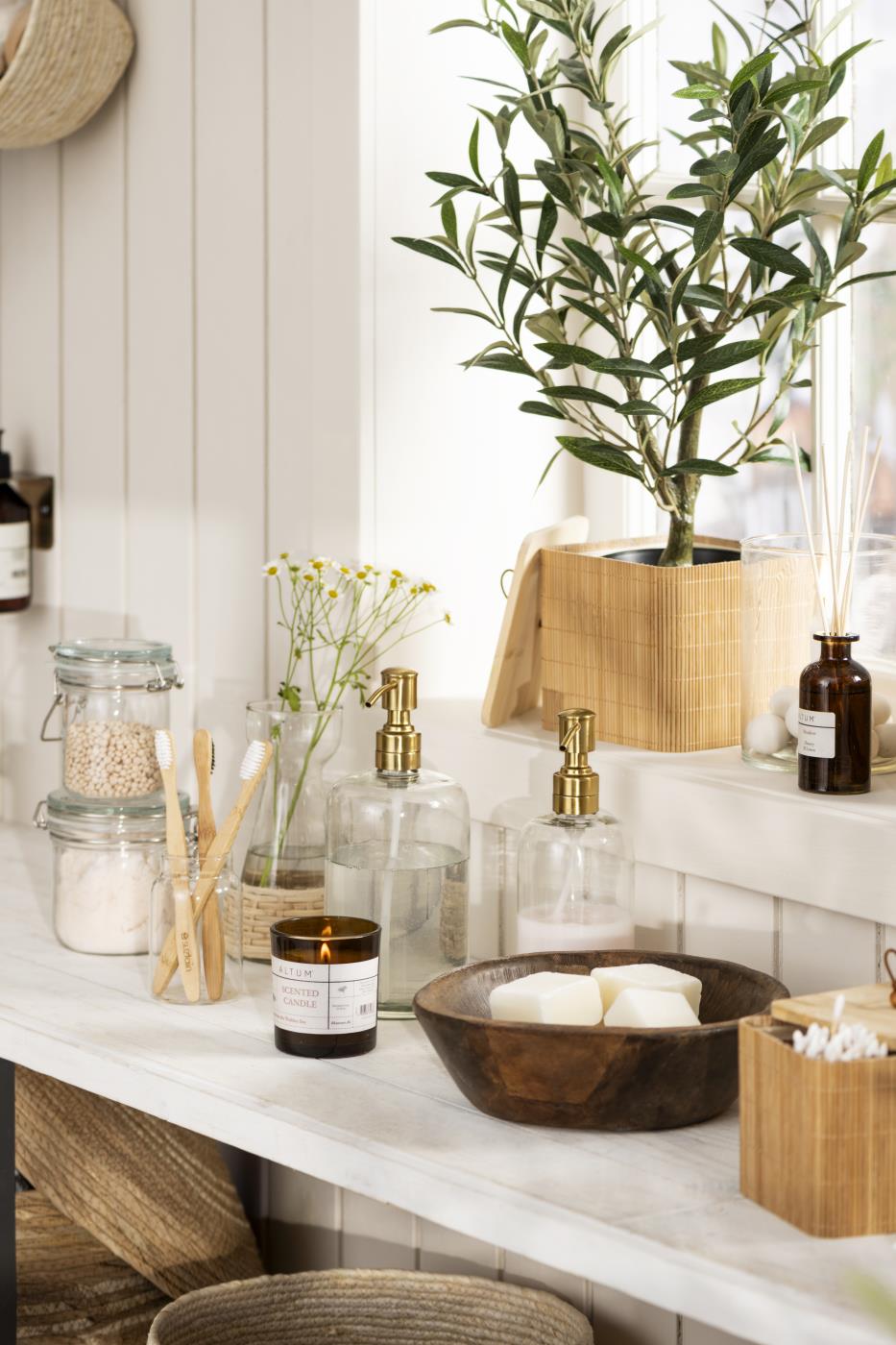 Soap dispenser with a brass-finish pump on a bathroom shelf with towels and toiletries