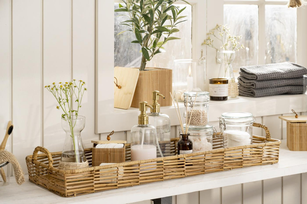 Glass soap dispenser from Ib Laursen on a tray with bathroom accessories and green plants